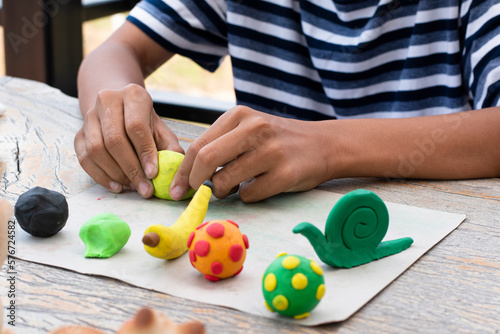 Asian boys spending free time with modeling clays at home by molding plasticine into the shapes of animals, fruits and other things at home, in motion.