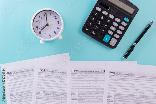 Tax fill concept, clock, pen and calculator  with 1040 U.S. form on blue or green backgound color