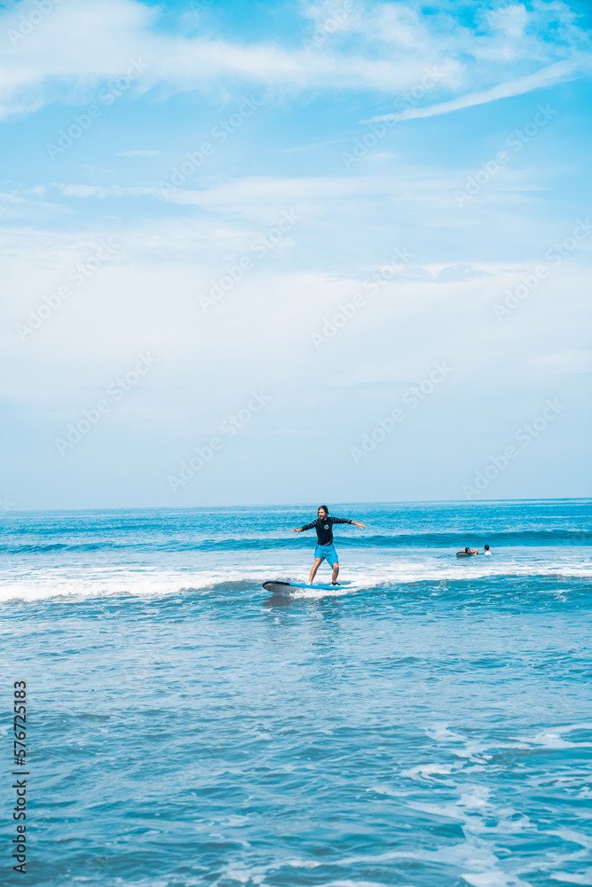 The man is surfing. A novice surfer on the waves in the ocean off the coast of Asia on the island of Bali in Indonesia.