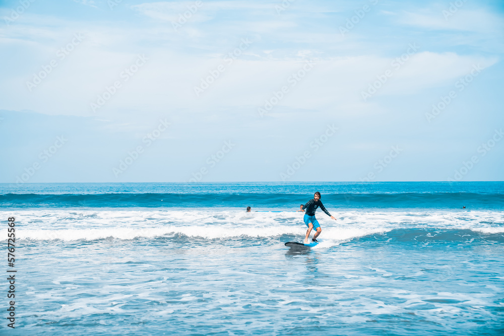 The man is surfing. A surfer on the waves in the ocean off the coast of Asia on the island of Bali in Indonesia. Sports and extreme. Beauty and health. Fashion and beach style.