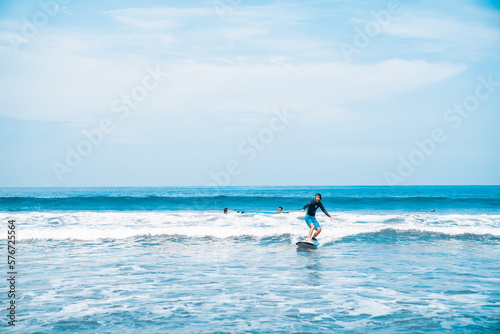 The man is surfing. A surfer on the waves in the ocean off the coast of Asia on the island of Bali in Indonesia. Sports and extreme. Beauty and health. Fashion and beach style. © algrigo