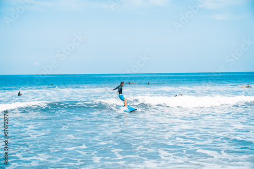 The man is surfing. A surfer on the waves in the ocean off the coast of Asia on the island of Bali in Indonesia. Sports and extreme. Beauty and health. Fashion and beach style. © algrigo