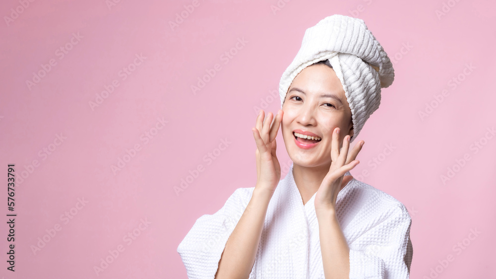 Beautiful young asian woman happy with clean face skin in towel and bathrobe, spa suit on pink background. Skincare, treatment, wellness therapy, facial care, beauty female health, cosmetology concept Beautiful young asian woman happy with clean face skin in towel and bathrobe, spa suit on pink background. Skincare, treatment, wellness therapy, facial care, beauty female health, cosmetology concept