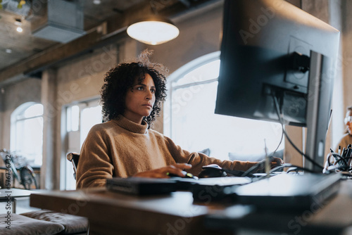 Dedicated female hacker working on computer at desk in startup company