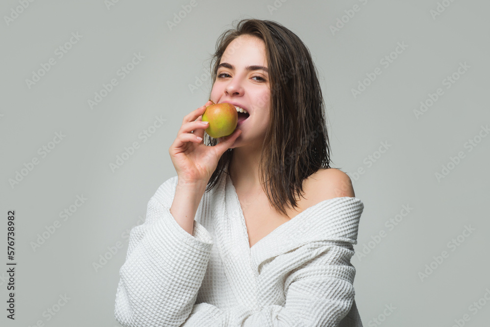 Young woman eating apple over grey isolated background. Girl eat apple. Dieting or dental health care, stomatology concept. Young woman eating apple over grey isolated background. Girl eat apple. Dieting or dental health care, stomatology concept.