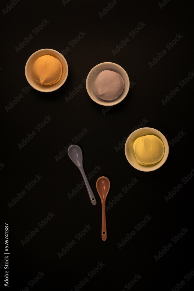 Colored spoons and marshmallows in cups on black. Still life Colored spoons and marshmallows in cups on black. Still life