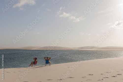 Casal de turistas relaxando sobre as dunas dos lençóis maranhenses na lagoa azul em Santo Amaro do Maranhão