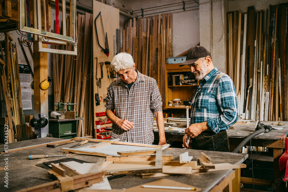 Senior craftsman discussing together while working at repair shop Senior craftsman discussing together while working at repair shop