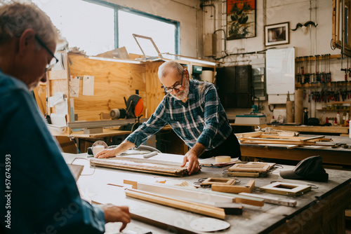 Senior male carpenter examining timber on workbench at repair shop photo