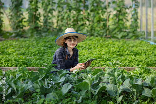 Asian woman farmer using digital tablet in vegetable garden at greenhouse, Business agriculture technology concept, quality smart farmer.