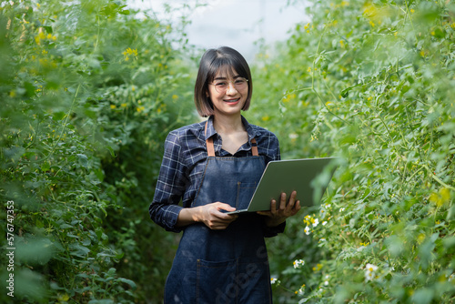 Smart farming and precision agriculture 4.0,  Asian farmer woman holding a laptop in a greenhouse. 