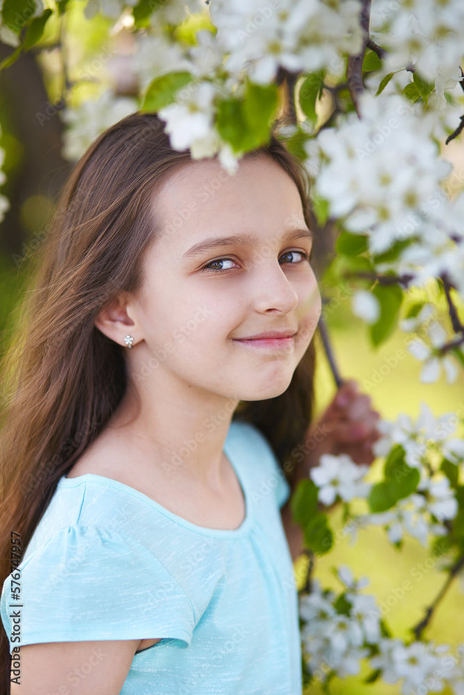 A beautiful young girl in a blooming apple orchard. Close-up. Vertical orientation A beautiful young girl in a blooming apple orchard. Close-up. Vertical orientation