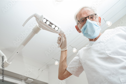 Close Up portrait of a mature experienced male doctor in glasses and face mask with dentist tools