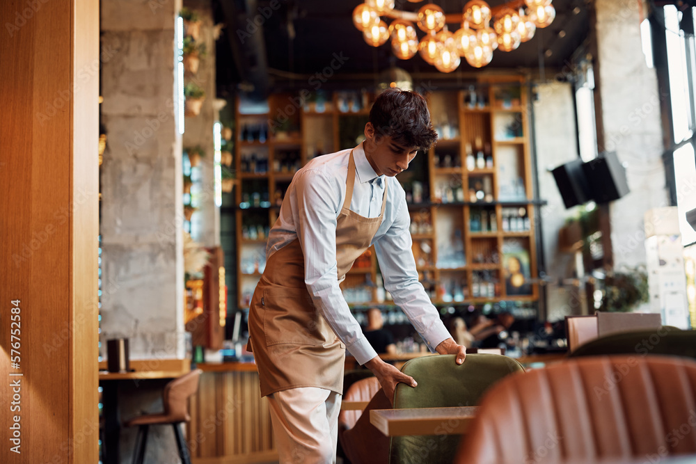 Waiter setting the tables while working in cafe. Waiter setting the tables while working in cafe.