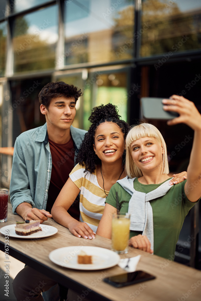 Multiracial group of friends take selfie with cell phone in cafe. Multiracial group of friends take selfie with cell phone in cafe.