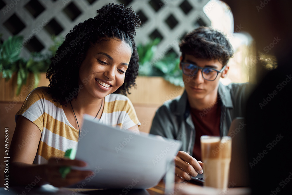 Happy black student and her friend preparing for upcoming exams in cafe. Happy black student and her friend preparing for upcoming exams in cafe.