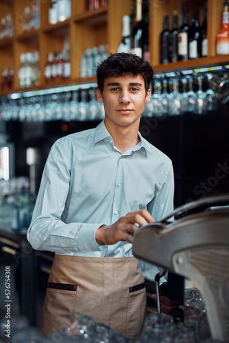 Obraz na plátně Young waiter preparing coffee and looking at camera.