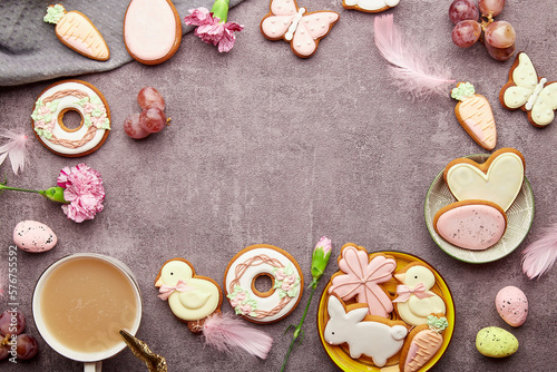 Easter aesthetic coffee time background. Glazed decorated cookies, coffee cup, feathers flat lay. Spring stylish background with copy space.