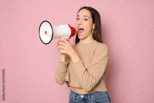 Young beautiful brunette woman screaming using megaphone over isolated pink background
