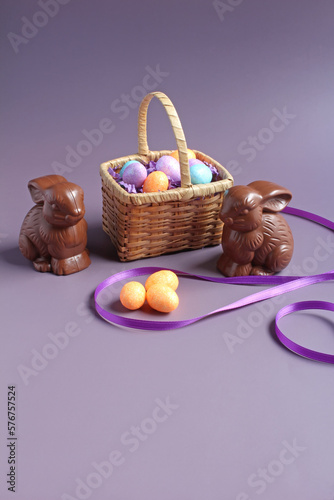 Chocolate bunnies, and Easter eggs in a small antique basket, with space for text.