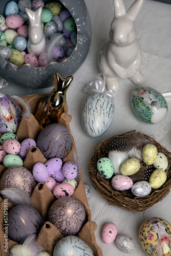photo colorful decorative chicken and quail eggs and a ceramic rabbit on the table