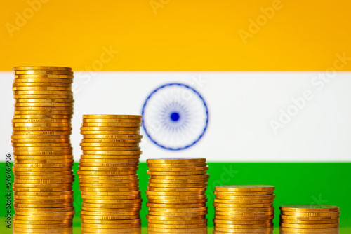 Flag of India with stacks of golden coins forming downcoming progression. Crisis in economy of India, negative process in finances of the country photo