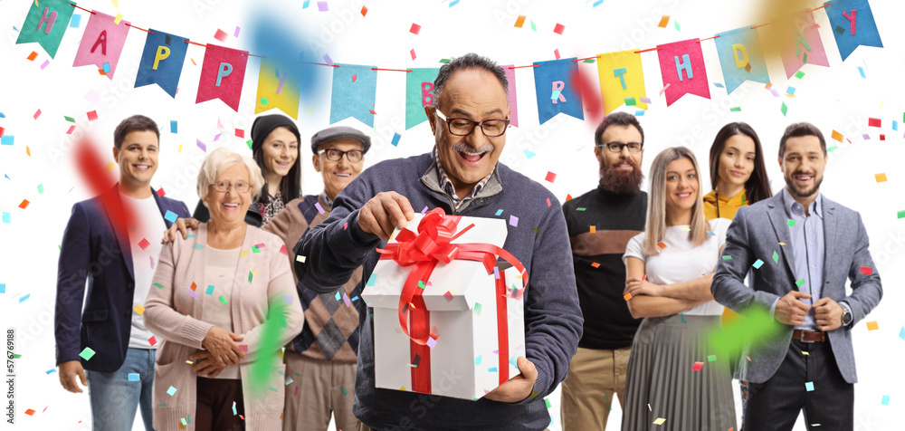 Happy mature man opening a gift box and people gathered at a celebration party