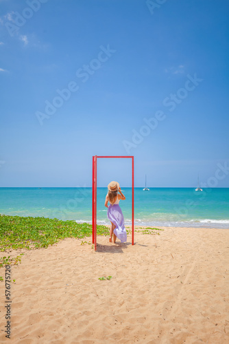 Tropical travel vacation. Traveler woman in red door on beach to turquoise sea