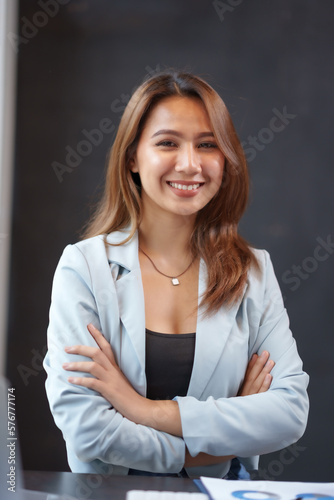 Beautiful asian businesswoman sitting crossed arms smiling looking at camera in office.