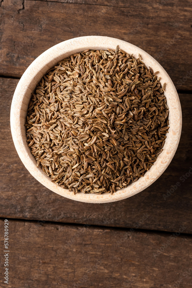 Dried cumin in bowl on wooden table. Close up. Top view Dried cumin in bowl on wooden table. Close up. Top view