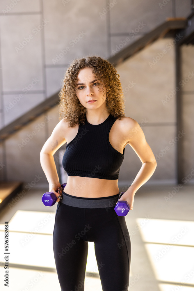 Sporty woman exercising with dumbbell at home to stay fit