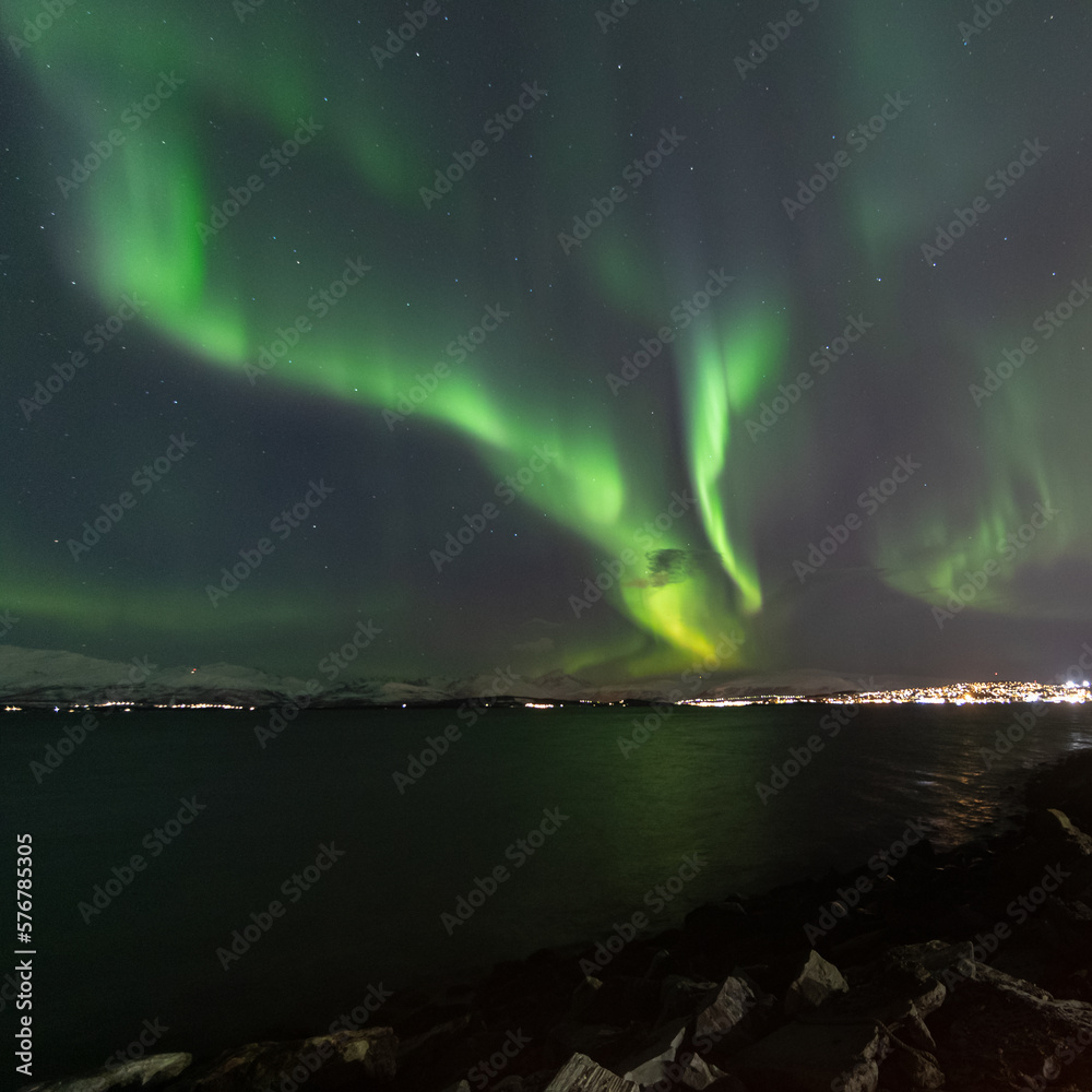 Aurora over the sea in Tromso. Northern light over town