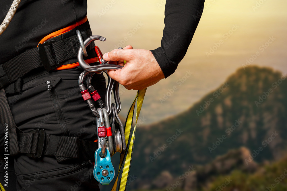 High-altitude equipment, carabiners, block rollers, on a man's belt. Telecommunications, work at height, industrial mountaineering, height, insurance. Close-up. In the mountains - obrazy, fototapety, plakaty 