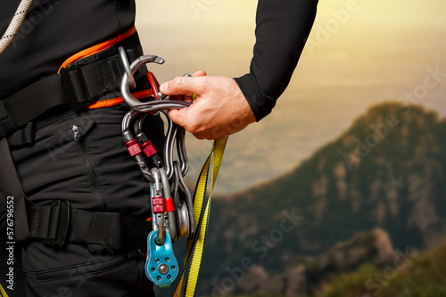 High-altitude equipment, carabiners, block rollers, on a man's belt. Telecommunications, work at height, industrial mountaineering, height, insurance. Close-up. In the mountains photo