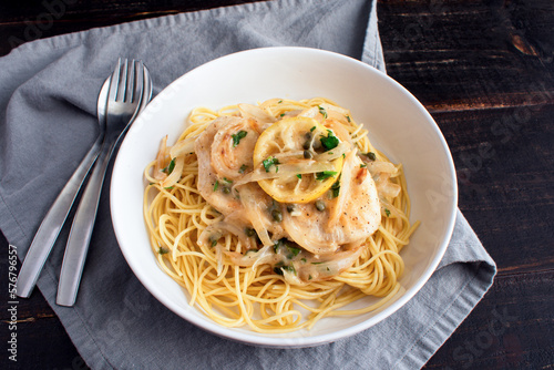 Chicken Piccata Served Over Spaghetti in a Pasta Bowl: Chicken, onions, and lemons in sauce made of garlic and white wine
