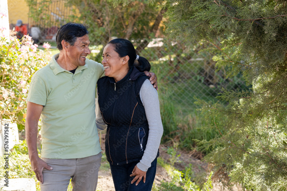 Portrait of hispanic couple hugging while smiling - Senior adult couple enjoying walk in the park - Latin retired adults Portrait of hispanic couple hugging while smiling - Senior adult couple enjoying walk in the park - Latin retired adults