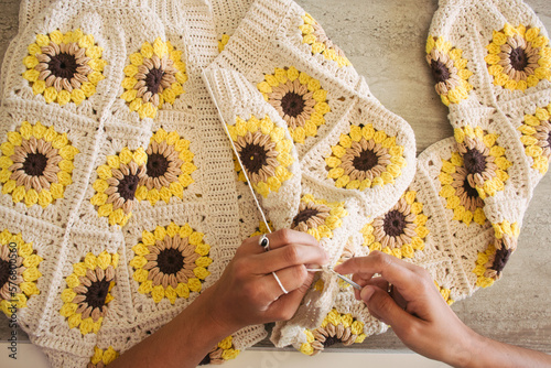Woman knitting at home cardigan with squares of sunflowers crochet grannys