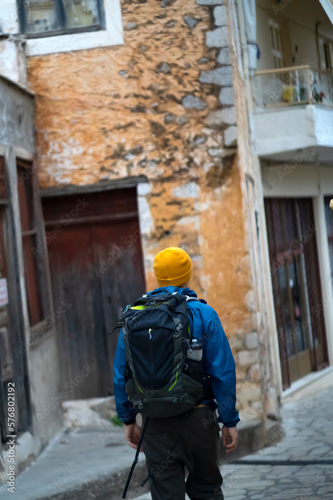 A man is travelling in the old town with a backpack.