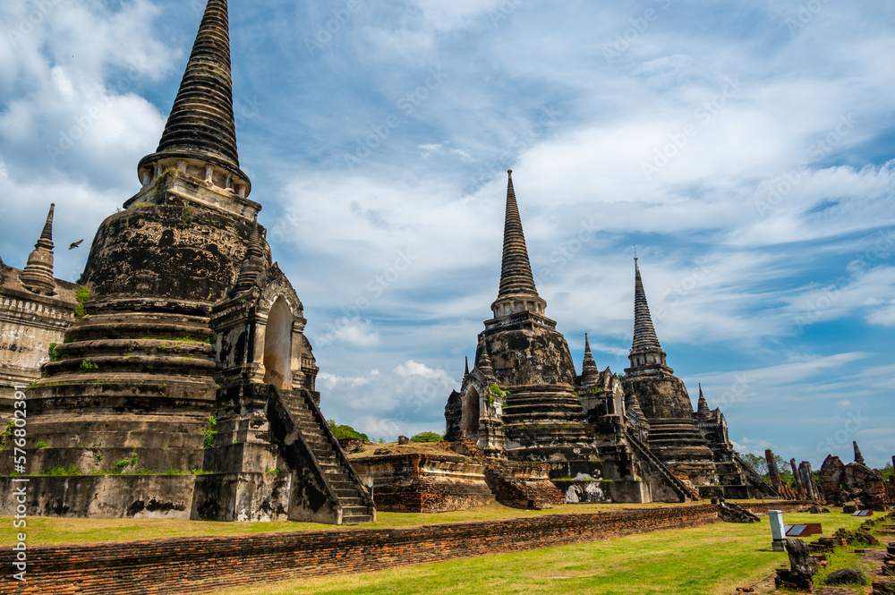 Fototapeta premium Ruins of ancient city and temples Ayutthaya, Thailand. Old kingdom of Siam. Summer day with blue sky. Famous tourist destination, spiritual place near Bangkok.