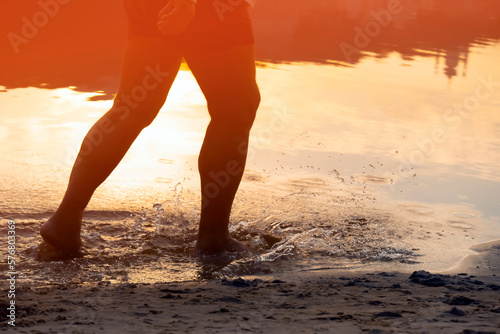 A man is running along the coast, training, legs and water closeup.
