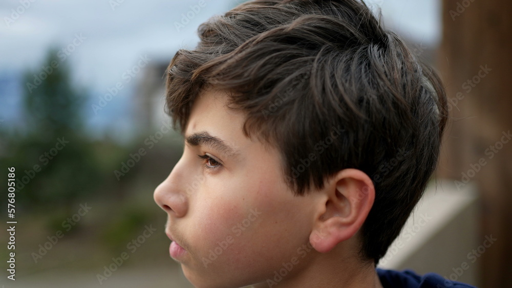 Teen kid stands at park outside staring at horizon in meditation. Tracking shot of young boy in contemplation Teen kid stands at park outside staring at horizon in meditation. Tracking shot of young boy in contemplation