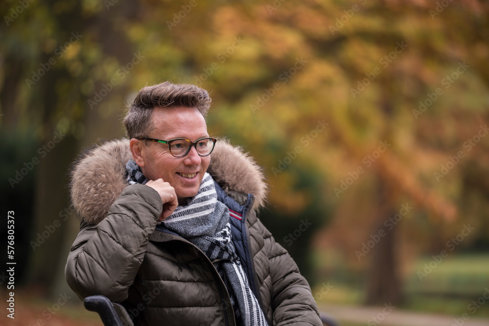 Caucasian man sitting on a bench in a park during autumn looking into the scenery Caucasian man sitting on a bench in a park during autumn looking into the scenery
