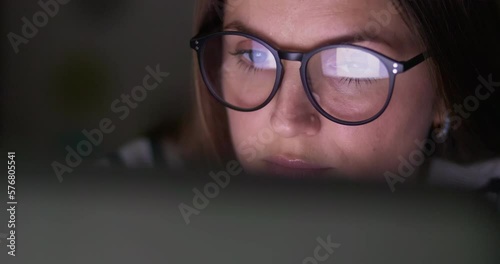 Close up view of focused woman in glasses looking at laptop screen