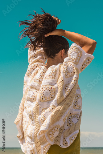 woman on the beach wearing a crochet cardigan made with granny squares, crochet outfit.Outfit spring summer