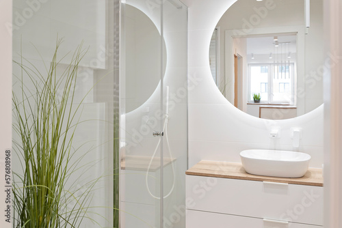 Leinwand Poster Luxury bathroom with glass to shower, round mirror with led lights, stylish washbasin and wooden cabinet