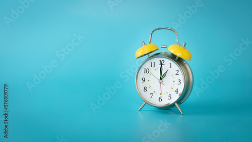 Retro silver alarm clock. 1:00, am, pm. Blue background.