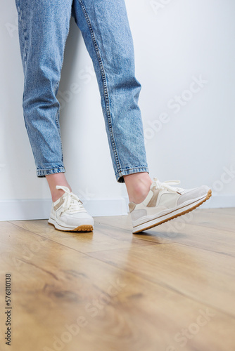 Close-up of female legs in jeans and casual sneakers. Women's comfortable casual shoes. White leather women's sneakers