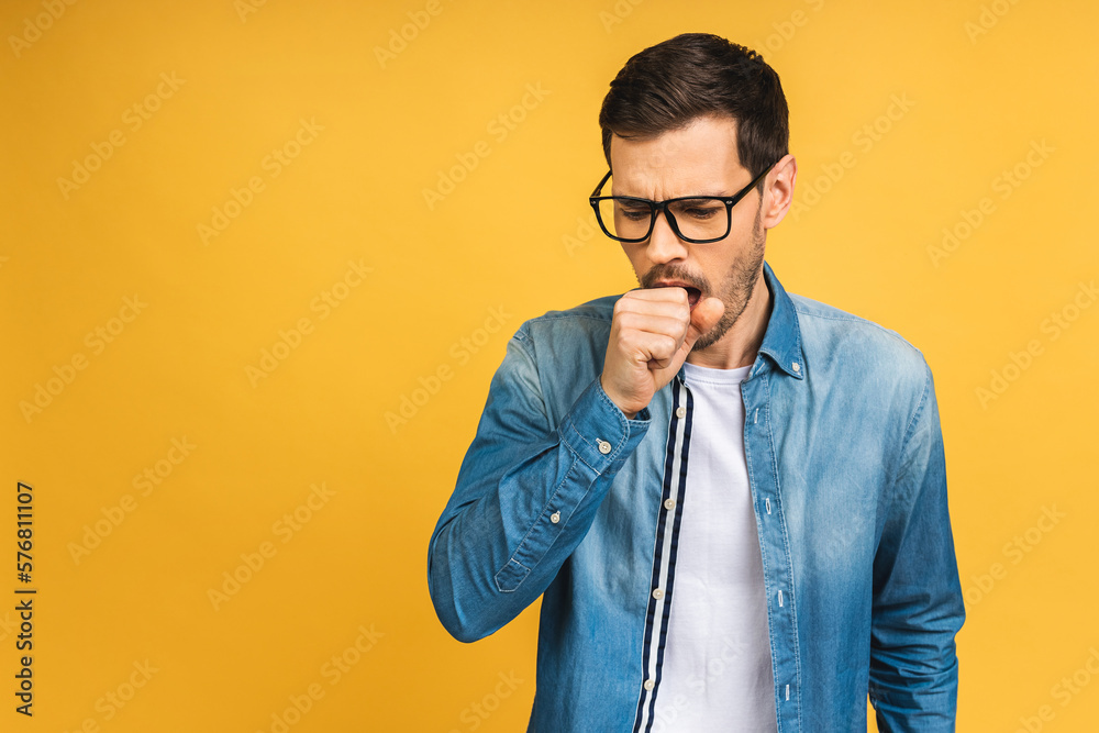Sore throat. Young bearded men coughs isolated against yellow background. Cold and flu concept.