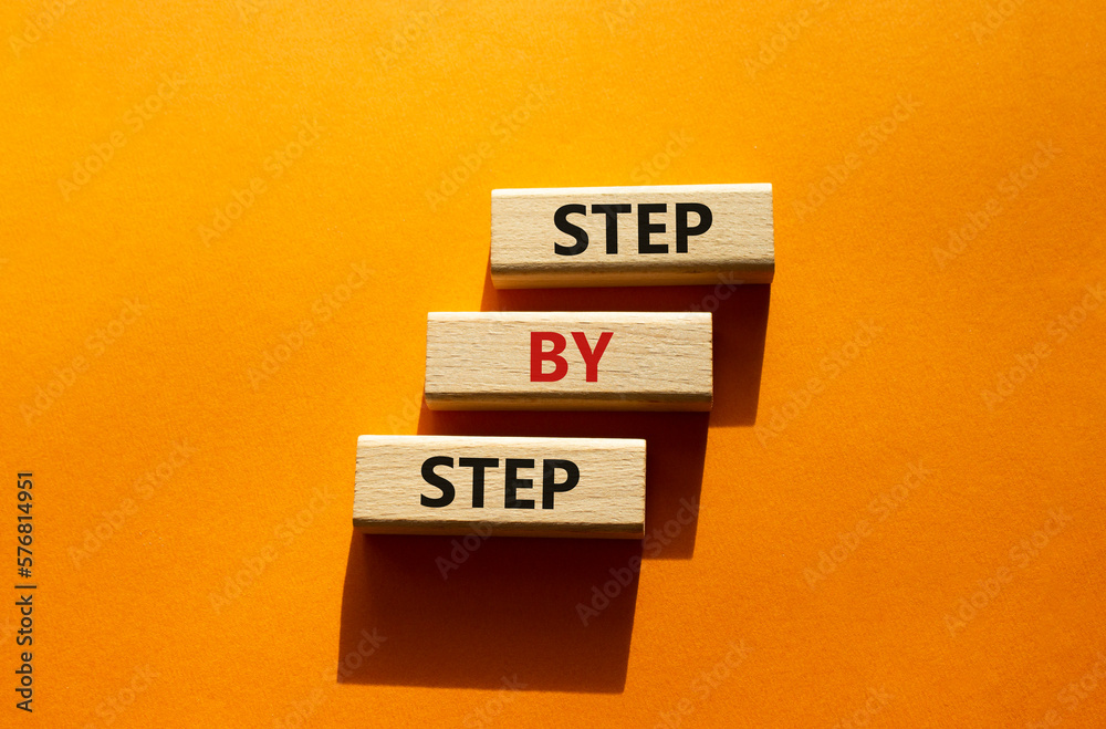 Step by step symbol. Wooden blocks with words Step by step. Beautiful orange background. Business concept. Copy space.
