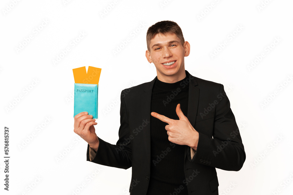 Handsome young smiling man wearing jacket is pointing at the passport he holds. Handsome young smiling man wearing jacket is pointing at the passport he holds.